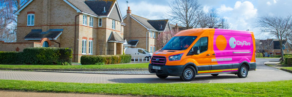 Photo of a bright pink and orange CityFibre branded van parked on a modern housing estate