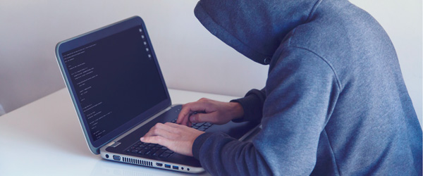 man wearing hoodie with hood up using laptop